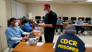 Instructor Douglas Arnwine hands back papers with comments to his incarcerated students during a Mount Tamalpais College English class called Cosmopolitan Fictions at San Quentin State Prison