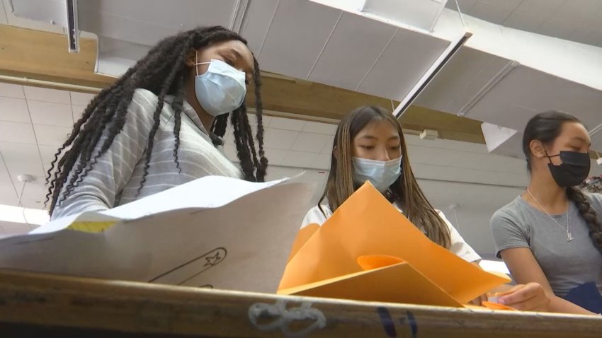 Girls stand over a table covered with envelopes