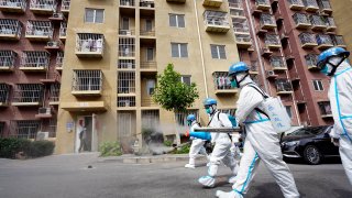Shanghai and Beijing have retained, if not tightened, many Covid-related restrictions on business and travel. In this picture, workers disinfect a residential community on May 11, 2022, in Beijing, China.
