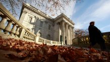 A woman walks past the front entrance to Marble House mansion, in Newport, R.I.