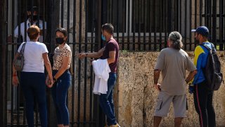 People wait their turns outside the U.S. embassy the day after it reopened its consular services in Havana, Cuba, Wednesday, May 4, 2022.