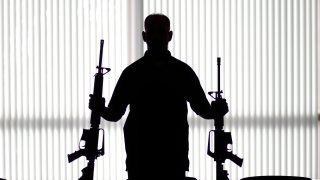 An ATF agent poses with homemade rifles, or "ghost guns," at an ATF field office in Glendale, Calif