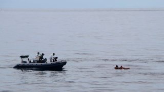 In this photo released by the National Search and Rescue Agency (BASARNAS), rescuers retrieve survivors floating on a wooden plank during a search for victims of a sinking cargo boat in the Makassar Strait, Indonesia, Sunday, May 29, 2022.