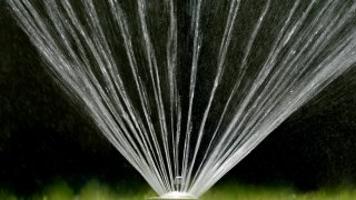 Water flies from a sprinkler on a lawn in Sacramento, Calif., on July 8, 2021. California Gov. Gavin Newsom threatened Monday, May 23, 2022, to impose mandatory, statewide restrictions on water use if people don't start using less on their own as the drought drags on and the hotter summer months approach.