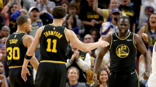 Golden State Warriors' Stephen Curry (30) and Klay Thompson (11) congratulate Draymond Green (23).