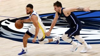 Stephen Curry #30 of the Golden State Warriors drives past Luka Doncic #77 of the Dallas Mavericks.