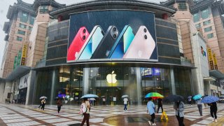 People walk past an apple store in Wangfujing with iPhone 13 series advertisement on a big screen.