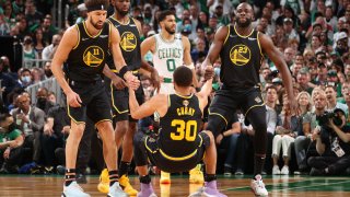 Klay Thompson #11 and Draymond Green #23 of the Golden State Warriors help up Stephen Curry #30.