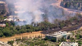 Firefighters battle a brush fire on the San Jose-Milpitas border.