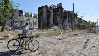A man stands with a bicycle next to apartment buildings destroyed during Ukraine-Russia conflict in the city of Sievierodonetsk in the Luhansk Region, Ukraine June 30, 2022.