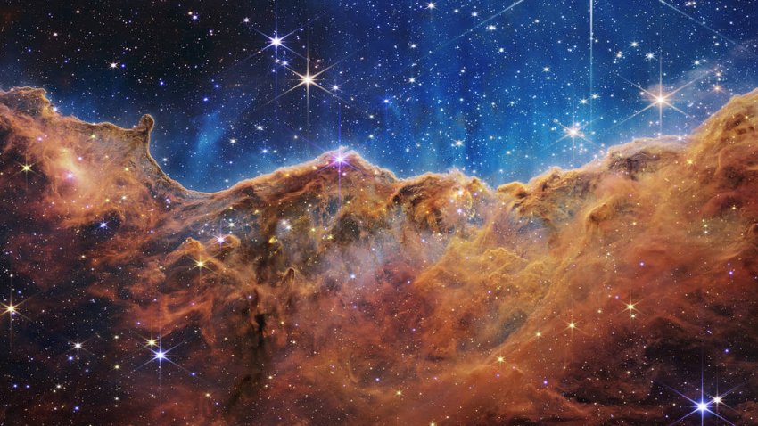 This landscape of “mountains” and “valleys” speckled with glittering stars is actually the edge of a nearby, young, star-forming region called NGC 3324 in the Carina Nebula. Captured in infrared light by NASA’s new James Webb Space Telescope, this image reveals for the first time previously invisible areas of star birth.