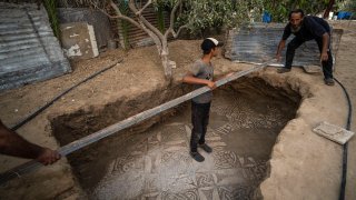 Palestinians clean around a Byzantine-era mosaic floor