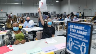 A Gwinnett county worker raises a piece of paper saying that they have a question as they begin their recount of the ballots on November 13, 2020 in Lawrenceville, Georgia.