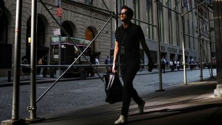 A man walks on Wall St. during the morning commute, as the city deals with record temperatures and the excessive heat, in New York, July 20, 2022.