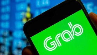 Singapore technology ride-sharing and food delivery service company Grab logo is displayed on a smartphone screen.