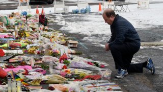 Colorado Gov. Jared Polis kneels in front of a memorial set up outside Club Q in Colorado Springs, Colo., Tuesday, Nov. 29, 2022.