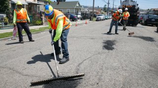 A maintenance crew repairs potholes.