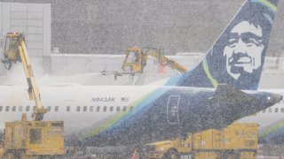 Workers deice an Alaska Airlines plane during a snow storm at Seattle-Tacoma International Airport (SEA) in Seattle, Washington, US, on Tuesday, Dec. 20, 2022.