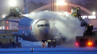 An American Airlines plane is de-iced as high winds whip around 7.5 inches of new snow at Minneapolis-St. Paul International Airport Thursday, December 22, 2022.