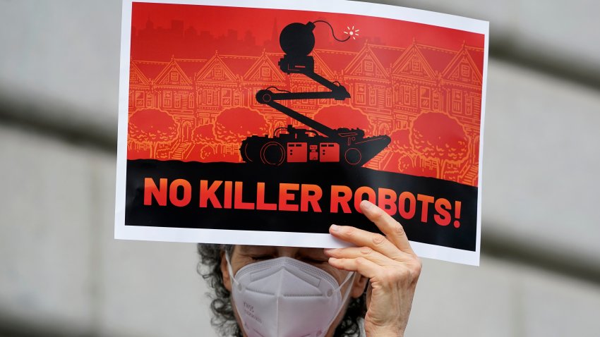 A woman holds up a sign reading "no killer robots!"