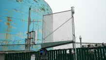 A small fog collector measuring about one square meter is mounted on a fence near water tanks in Pacifica, measuring the water that could be available to residents there if they were to collect fog at their homes.