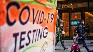 People wearing masks walk next to coronavirus disease (COVID-19) testing site in New York City, New York, U.S., December 12, 2022. 