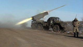 This grab taken from AFP video footage shows a member of Ukraine’s military looking away as a BM-21’Grad’ MLRS 122mm rocket launcher fires on the outskirts of Soledar on January 11, 2023.