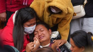 A woman wails as she waits to receive the body of a relative