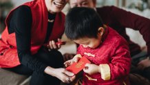 A little boy dressed in a Tang style red jacket receives a red envelope during Lunar New Year