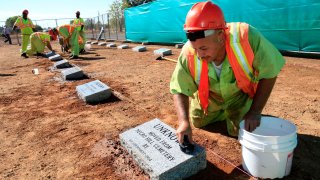 Steven Abujen, a California prison inmate with the Prison Industry Authority, cleans one of the newly installed headstones at the Mormon Island Relocation Cemetery, near Folsom, Calif., on Oct. 18, 2011.