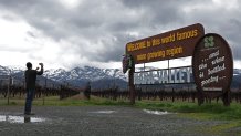 CALISTOGA, CALIFORNIA - FEBRUARY 24: Snow covers the hills near a vineyard as a man takes a photo of a sign on February 24, 2023 in Calistoga, California. A large winter storm brought snow to lower elevations overnight in the Napa Valley. Much of California is being impacted by a cold winter storm that is bringing rain, wind a snow below 1,500 feet in many locations. (Photo by Justin Sullivan/Getty Images)