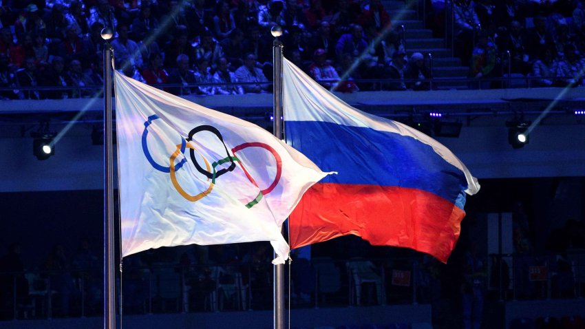 A picture taken on February 23, 2014 shows the Olympic flag and the Russian flag flying during the Closing Ceremony of the Sochi Winter Olympics at the Fisht Olympic Stadium.