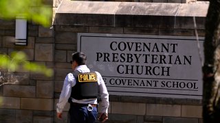 A police officer walks by an entrance to The Covenant School after a shooting in Nashville, Tenn., March 27, 2023.