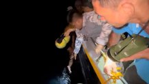 In this photo provided by the Philippine Coast Guard, Philippine Coast Guard personnel plucks a survivor from the waters near a burning MV Lady Mary Joy at Basilan, southern Philippines early Thursday March 30, 2023. More than a dozen people died while other were reported missing after an inter-island cargo and passenger ferry with about 200 passengers and crew onboard caught fire close to midnight in the southern Philippines, a provincial governor said Thursday. (Philippine Coast Guard via AP)