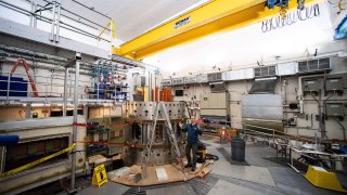 Physicist Stephen Wukitch stands next to the partially disassembled now defunct fusion reactor core at the Massachusetts Institute of Technology Plasma Science & Fusion Center in Cambridge, Massachusetts, on January 25, 2023. – The lab is working with partners to build a new fusion reactor testing core.