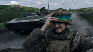 A Ukrainian soldier holds his helmet as he rides an APC in Bakhmut, in the Donetsk region, Ukraine, Wednesday, April 26, 2023.