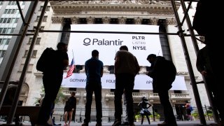People stand in front a banner displaying Palantir Technologies Inc. signage during the company’s initial public offering (IPO) in front of the New York Stock Exchange (NYSE) in New York, Sept. 30, 2020.