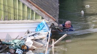 A local resident swims by a house in a flooded area in Kherson on June 7, 2023, following the destruction of Kakhovka hydroelectric power plant dam.