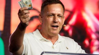 Peter Thiel, co-founder of PayPal, Palantir Technologies, and Founders Fund, holds hundred dollar bills as he speaks during the Bitcoin 2022 Conference at Miami Beach Convention Center on April 7, 2022 in Miami, Florida.