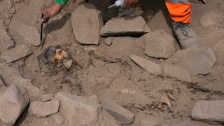 An archaeologist excavates a pre-Hispanic mummy that was discovered next to a training field for a Peruvian professional soccer team in the El Rimac neighborhood of Lima, Peru, Thursday, June 15, 2023.