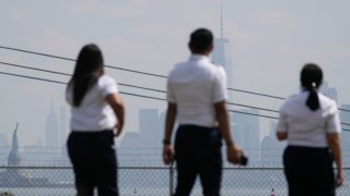 People look at the Statue of Liberty and the hazy New York City skyline from Bayonne, N.J., June 29, 2023.