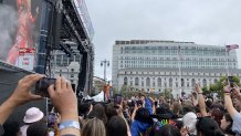 Hayley Kiyoko performs on a stage in San Francisco at the Pride Celebrations in an orange outfit while onlookers hold up their cell phones