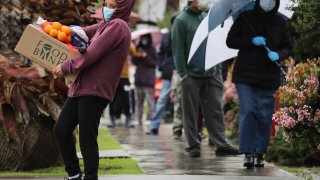 People wait in line at a food bank in Van Nuys, California, on April 9, 2020.