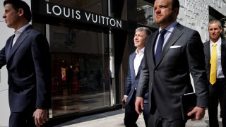 People walk past the Louis Vuitton store at Miami Design District, in Miami, Florida, November 30, 2021.