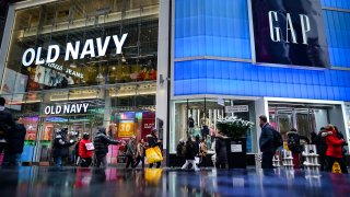 Pedestrians walk past Old Navy and GAP stores in Times Square, New York City.