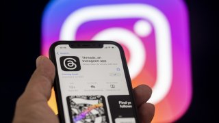 The logo of Threads is displayed on a mobile phone screen in front of a computer screen displaying the logo of Instagram in Ankara, Turkiye on July 04, 2023.
