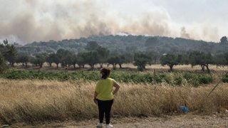 A woman looks at smoke from a wildfire some 50km southeast from the centre of Athens on July 17, 2023.