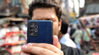 A man takes a photo with a Samsung phone with multiple cameras in Old Delhi, India on Oct. 28, 2022.