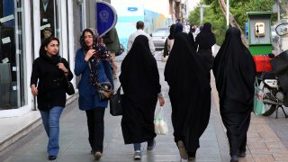 FILE – Iranian women make their way along a sidewalk in downtown Tehran, Iran, Tuesday, April 26, 2016. Iranian police have announced a new campaign to force women to wear the Islamic headscarf. Morality police returned to the streets on Sunday, 10 months after the death of a woman in their custody sparked nationwide protests. (AP Photo/Vahid Salemi, File)