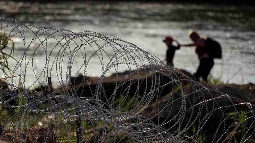 Migrants walk along concertina wire as they try to cross the Rio Grande at the Texas-U.S. border in Eagle Pass, Texas, July 6, 2023.